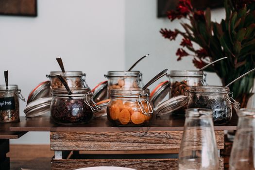 Assorted dried fruits and nuts in transparent jars on table