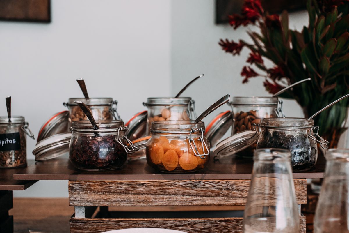 Collection of delicious sweet dried fruits and crunchy nuts in glass jars on wooden table in daytime