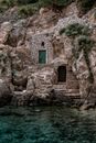 Aged masonry fortress facade with doors and green plants on mountain near rippled Adriatic Sea in Europe