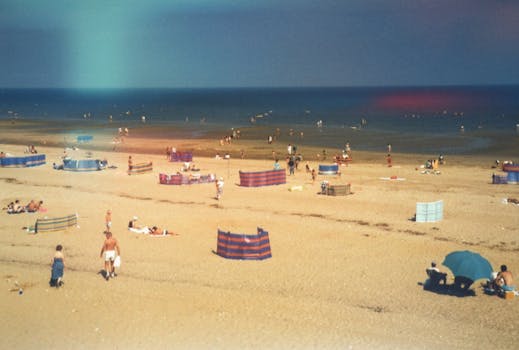 A vibrant summer day on a sandy Norfolk beach with people enjoying leisure activities by the sea.