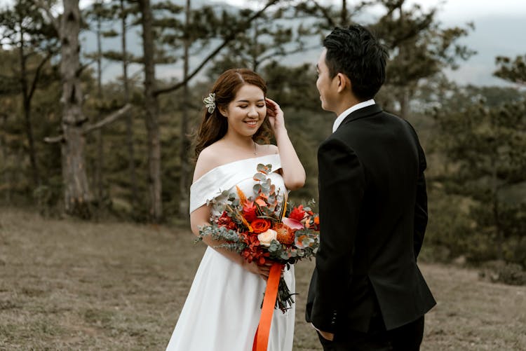 Asian Couple With Vivid Bouquet Walking In Forest