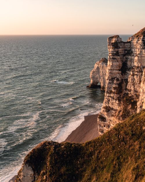 Free Explore the breathtaking cliff formations of Étretat, captured during a serene sunset over the English Channel in Normandy, France. Stock Photo