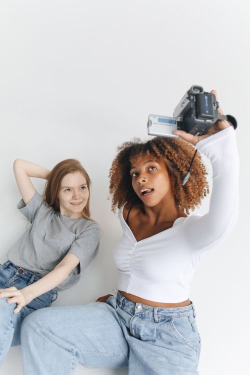 Free Two young women capture a fun moment together with a retro camera. Stock Photo