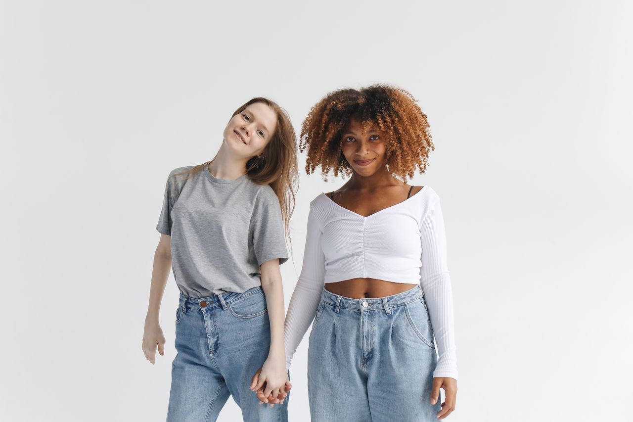 two women with diverse backgrounds smiling and holding hands showcasin