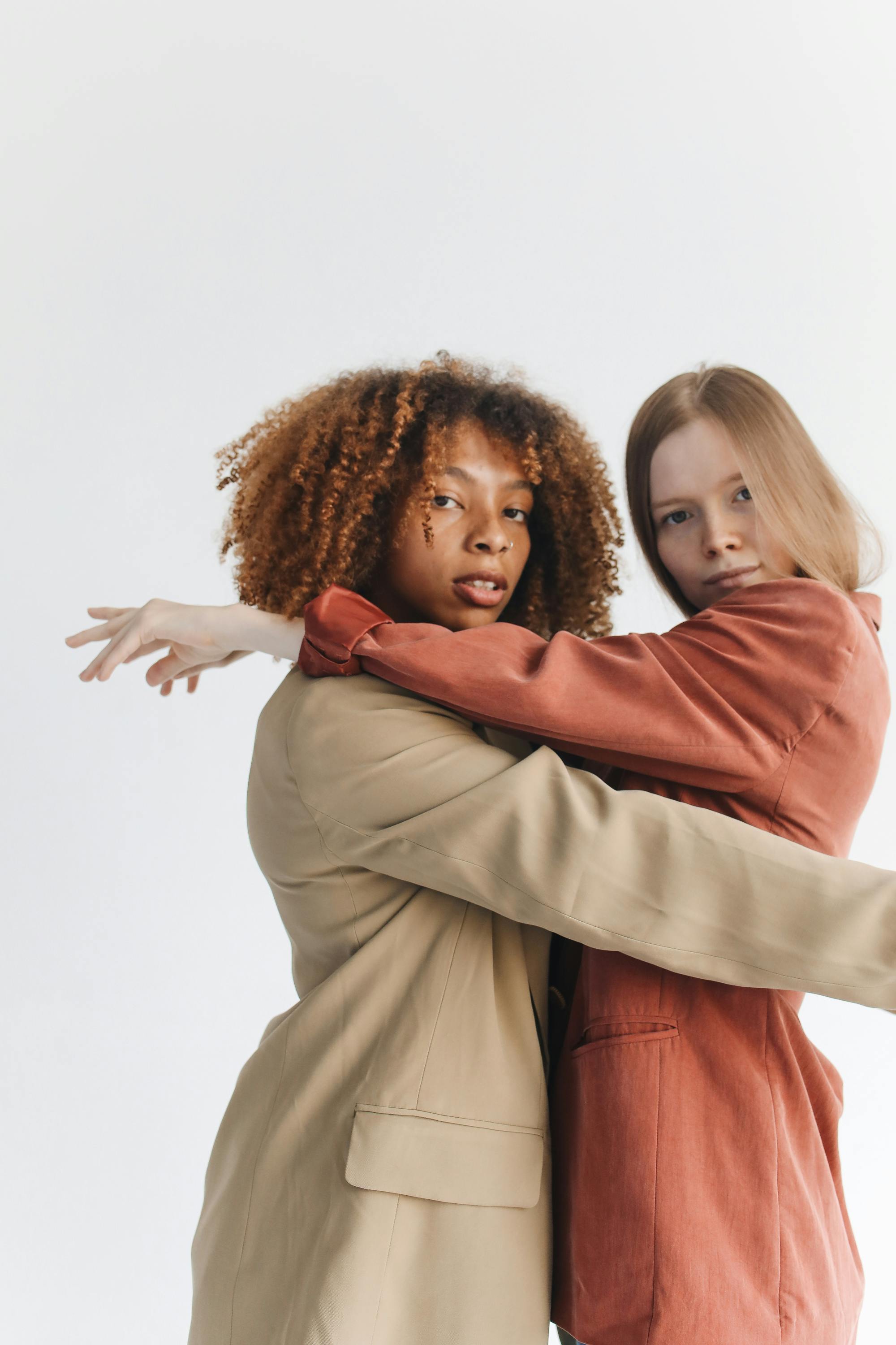 两位身着时尚西装外套的女性相拥，展现了友谊与时尚