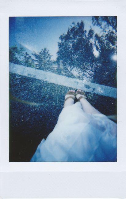 Polaroid photo showing feet on a reflective surface with an artistic vibe.