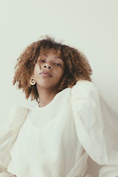 一位身着优雅白色服装、卷发的黑人女性时尚肖像，展现现代风尚