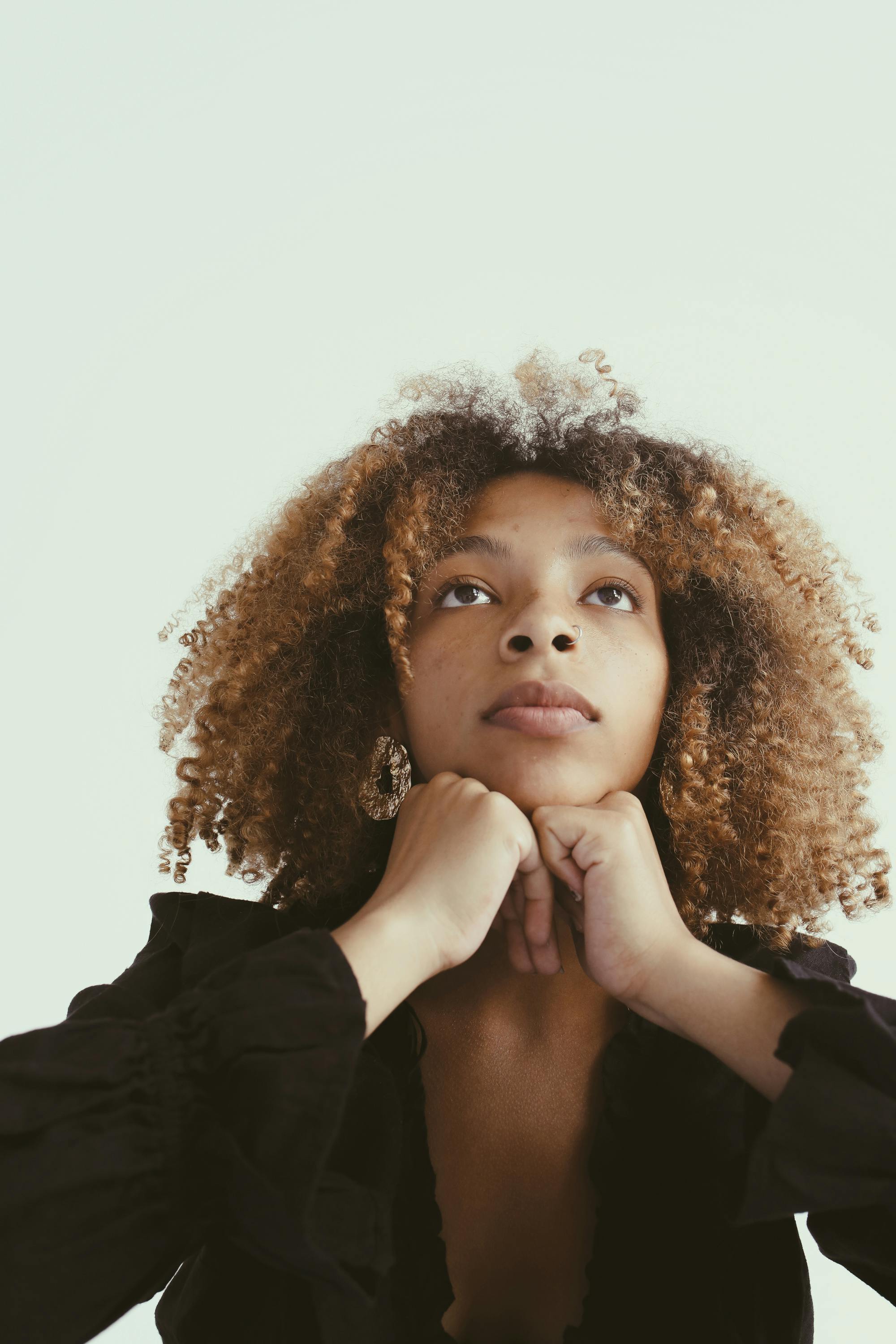 一位卷发的年轻非裔美国女性的特写肖像，陷入沉思