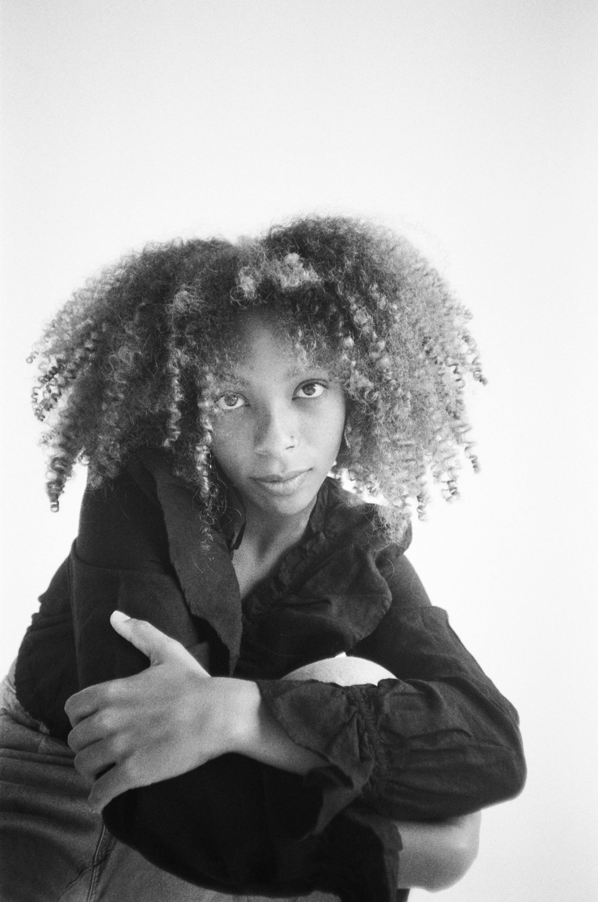 Stylish black and white portrait of a young woman with curly hair, exuding elegance.