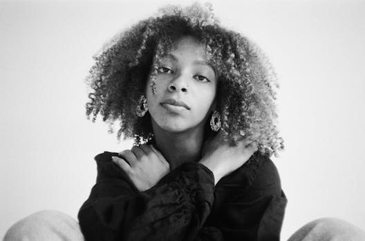 一张引人注目的单色特写中，一位留着非洲式发型、戴着耳环的女性格外醒目