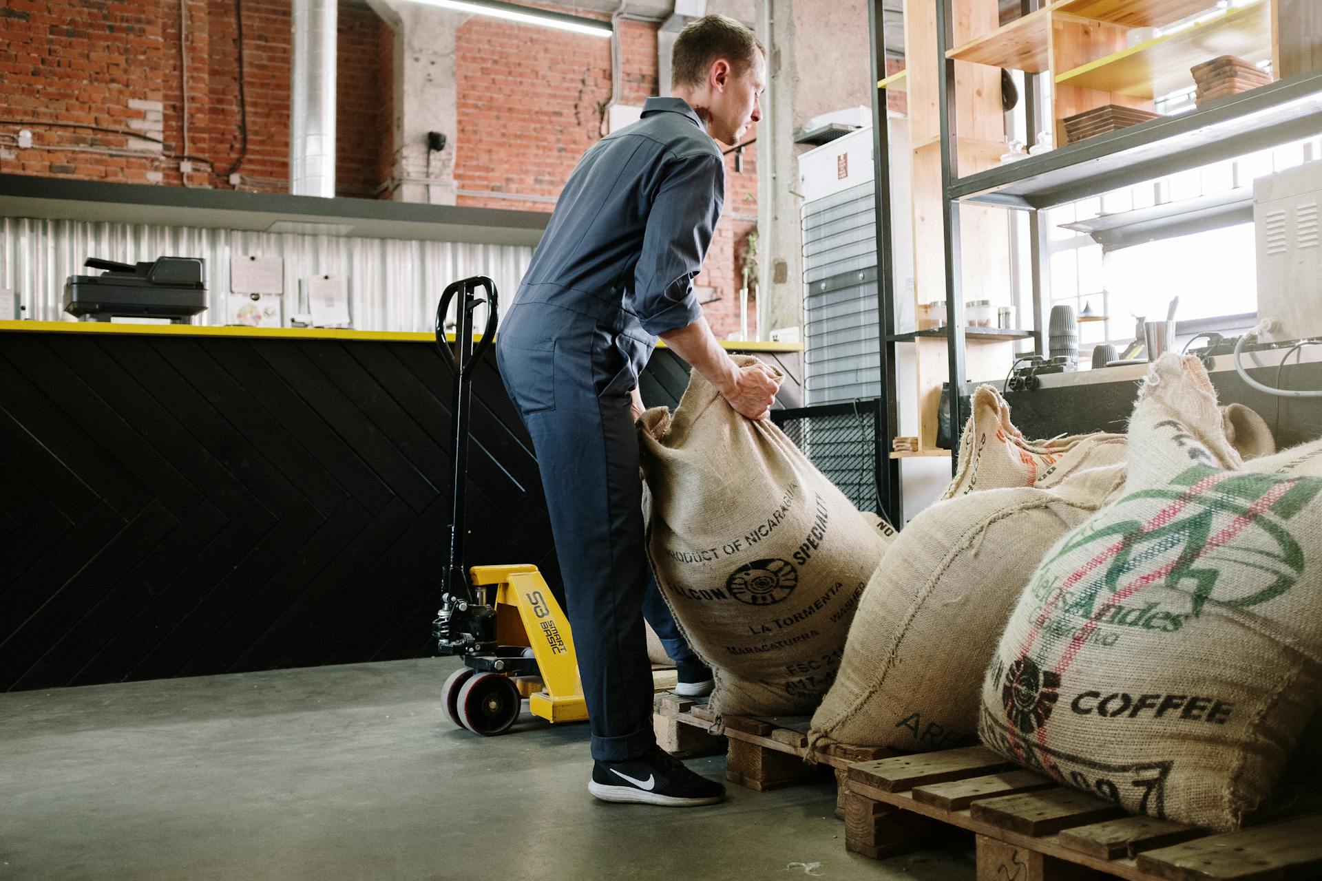 Man lifting coffee sacks in industrial interior with warehouse atmosphere.