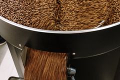 Close-up of coffee beans being roasted in an industrial machine, emphasizing motion and production.