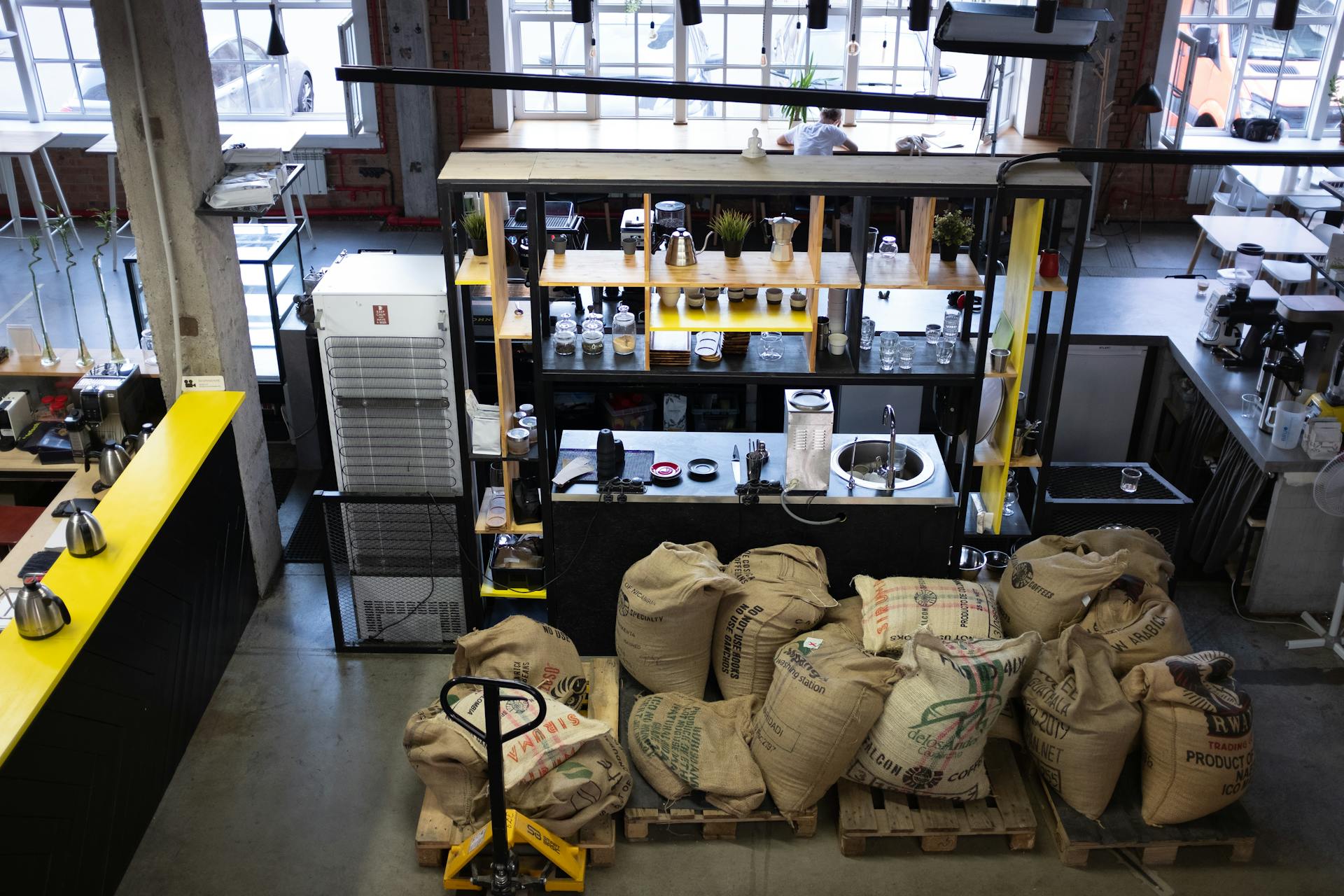 High angle view of a coffee shop interior featuring bean sacks and a well-organized workspace.