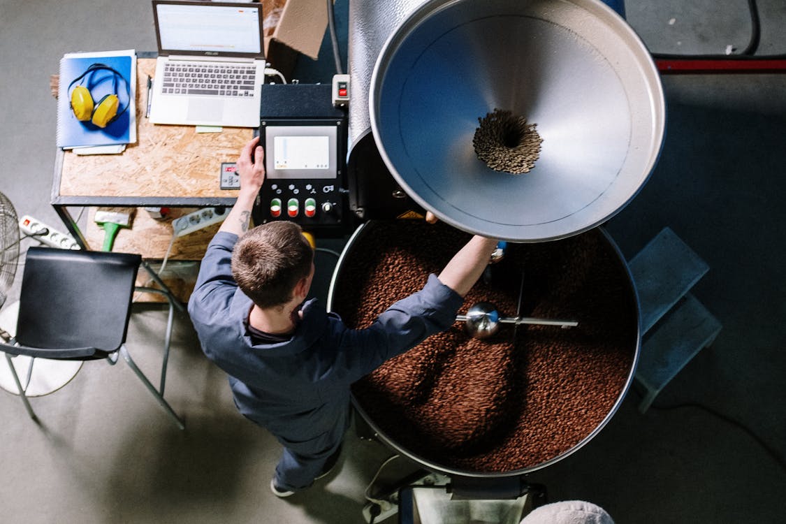Man operating a large drum coffee roaster
