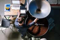 在工业环境中，咖啡烘焙店的一名工人操作设备加工新鲜咖啡豆