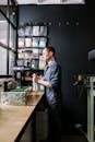 Man in Black Dress Shirt Standing Near Brown Wooden Table