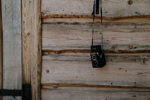 Free Hanging Lubitel 166 vintage twin lens camera on rustic wooden plank wall. Stock Photo