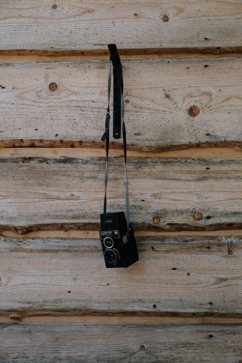 Free A classic Lubitel 166 twin lens reflex camera hangs against a rustic wooden texture. Stock Photo