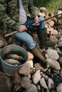 Man in Green Jacket and Blue Denim Jeans Holding Black and Gray Fishing Rod