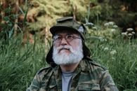 一位白胡子老人在户外绿地上穿着迷彩服