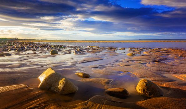 Captivating beach scene with rocks and moody sky during sunset, ideal for peaceful nature visuals.