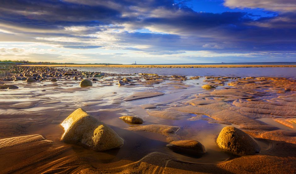 Captivating beach scene with rocks and moody sky during sunset, ideal for peaceful nature visuals.