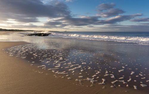 A Beach Waves Crashing on Shore Under the Blue Sky and White Clouds ...