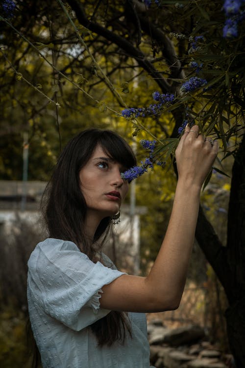 Woman in White Shirt Holding Purple Flowers