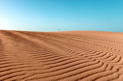 Free Stunning desert landscape with rippled sand dunes under a vibrant blue sky in Spain. Stock Photo
