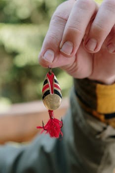 Detailed close-up of a person's hand holding a fishing lure, perfect for anglers and outdoor enthusiasts.