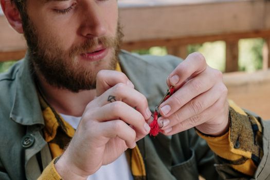 Close-up of a bearded man holding and preparing fishing tackle outdoors.