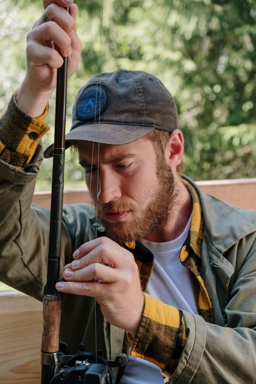 Free A focused fisherman carefully sets up his fishing rod outdoors in a natural setting. Stock Photo