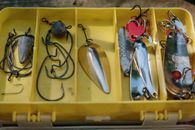 Close-up view of a yellow tackle box containing various fishing lures and hooks.