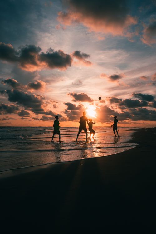 Free Silhouettes playing volleyball at sunset on a picturesque beach, creating a beautiful coastal scene. Stock Photo