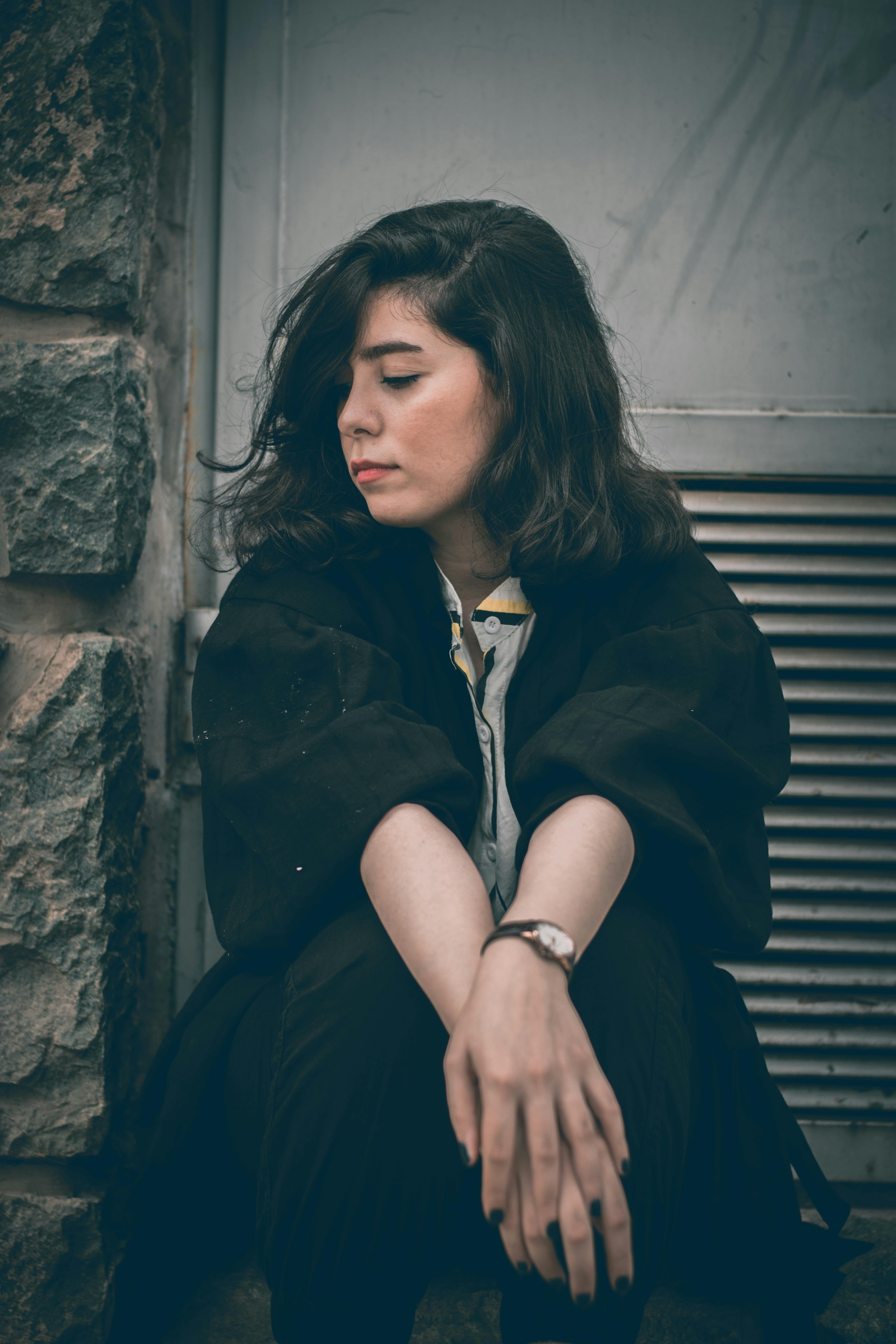 一名妇女侧身坐在石墙上沉思