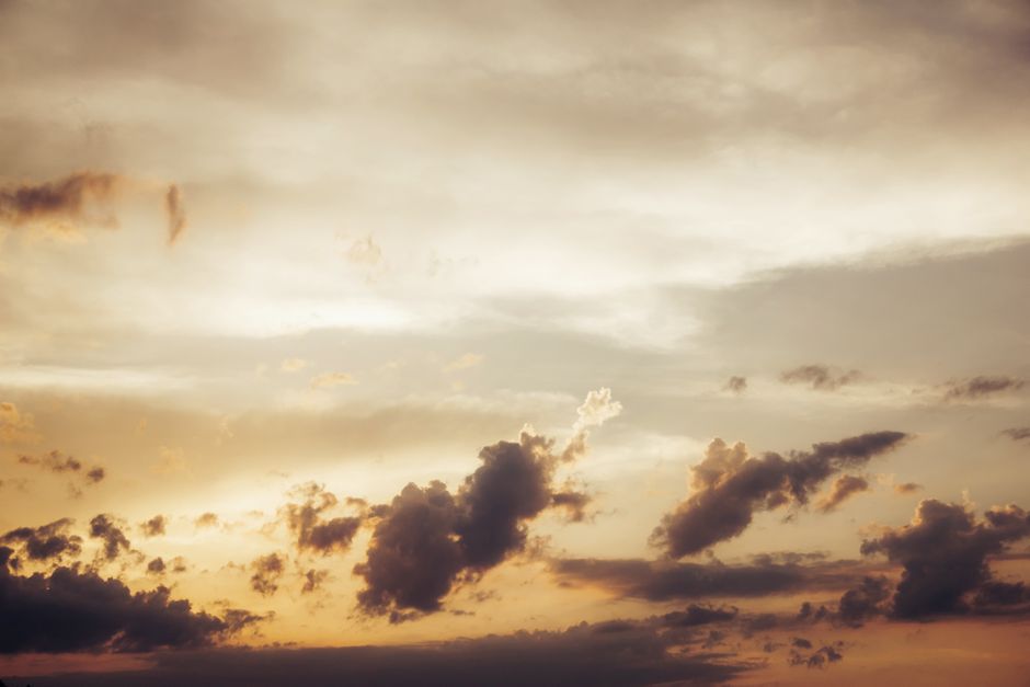 A serene and dramatic cloudscape during dusk with warm colors and scattered clouds.