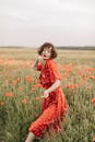 Girl in Red Dress Standing on Red Flower Field