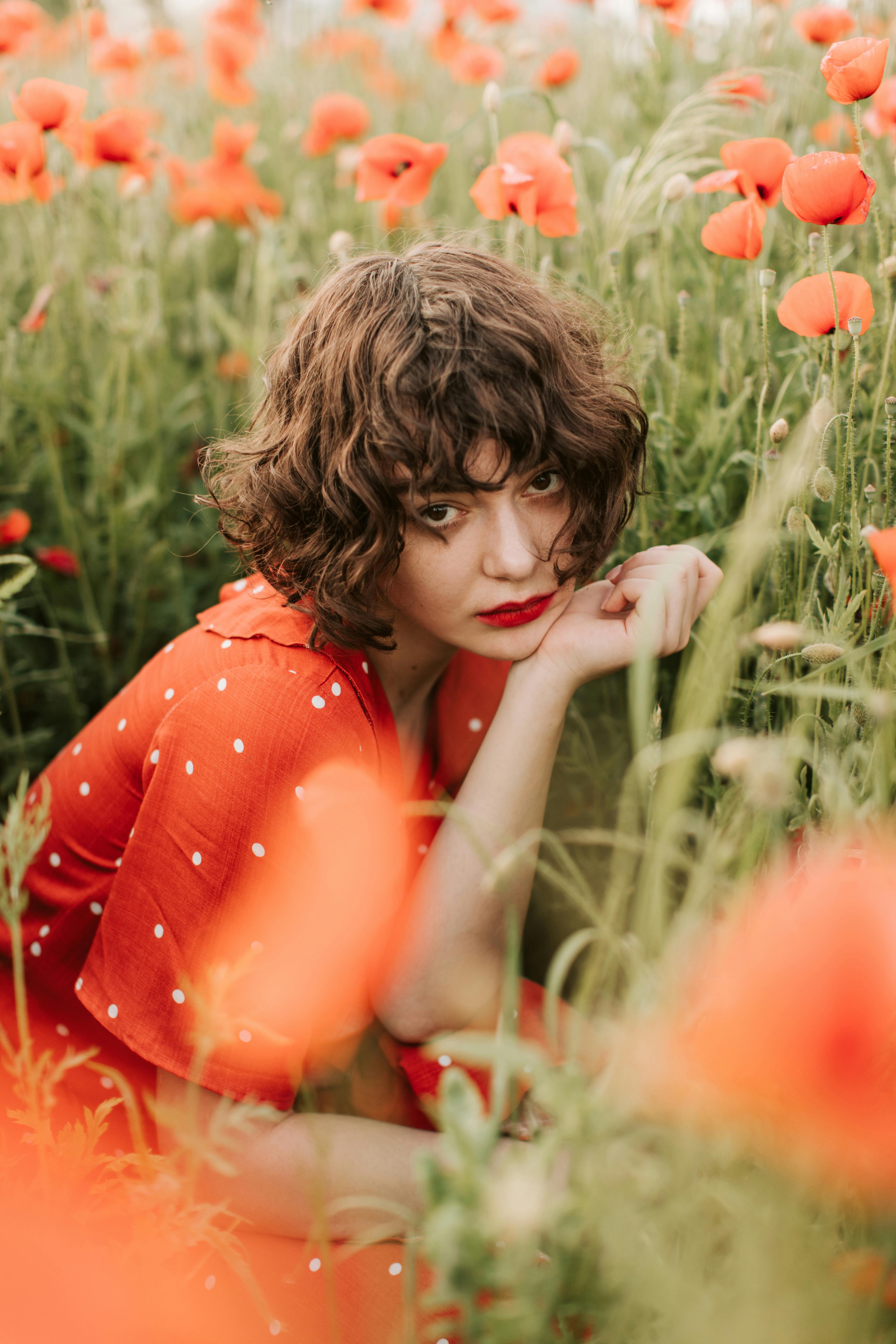 woman in red lipstick surrounded by red poppy flowers