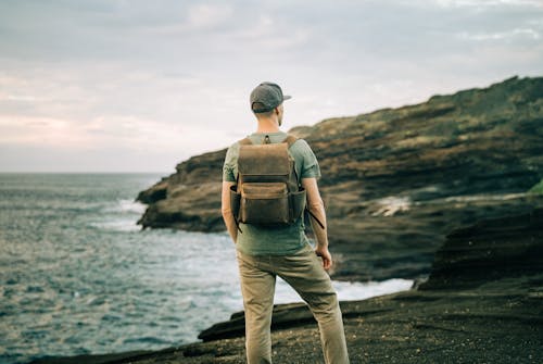Man with Backpack Contemplating at Rocky Coast