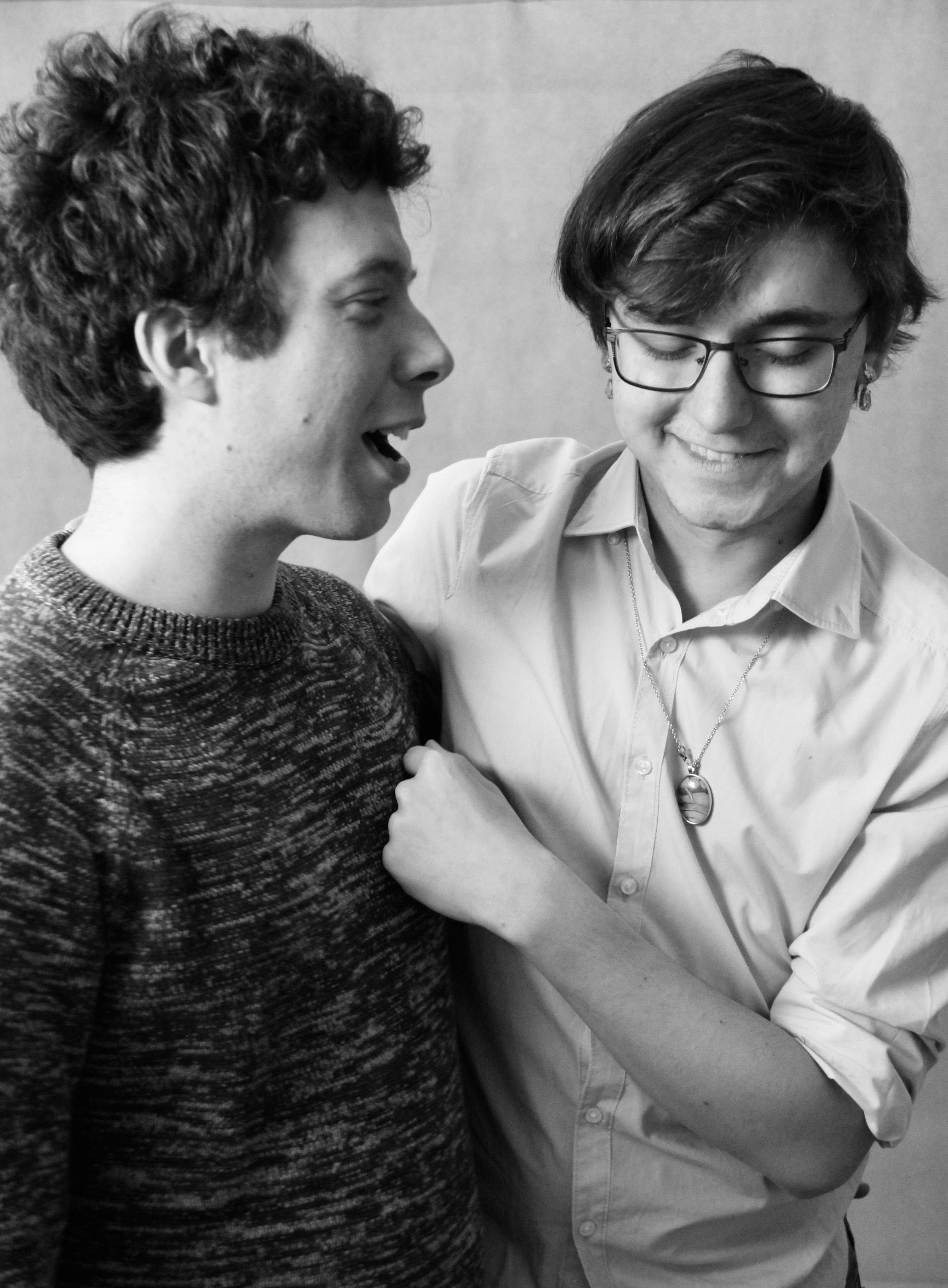 Intimate black and white portrait of two smiling men in a warm, close embrace.