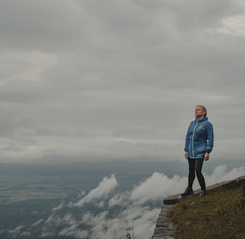 Free Woman Standing Near a Cliff Edge Stock Photo