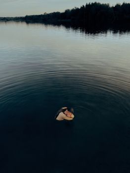 黄昏时分，一个女人独自在广阔宁静的湖中陷入沉思