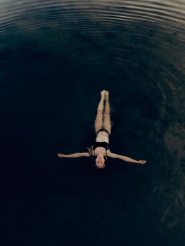 一名女子身着泳衣，平静地漂浮在宁静的水面上，漾起圈圈涟漪