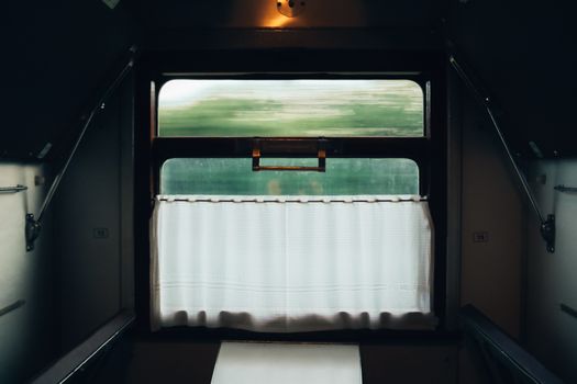 在老式火车车厢里，透过窗帘和窗户，可以看到动人的风景