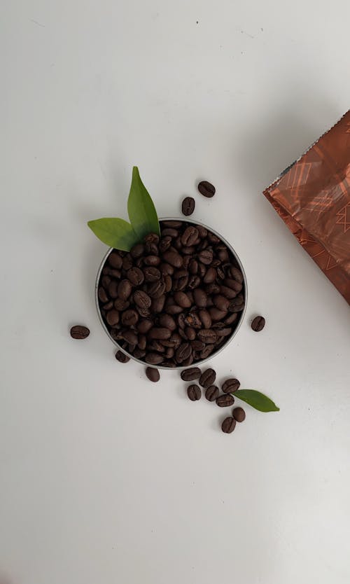 Roasted coffee beans with green leaves on table