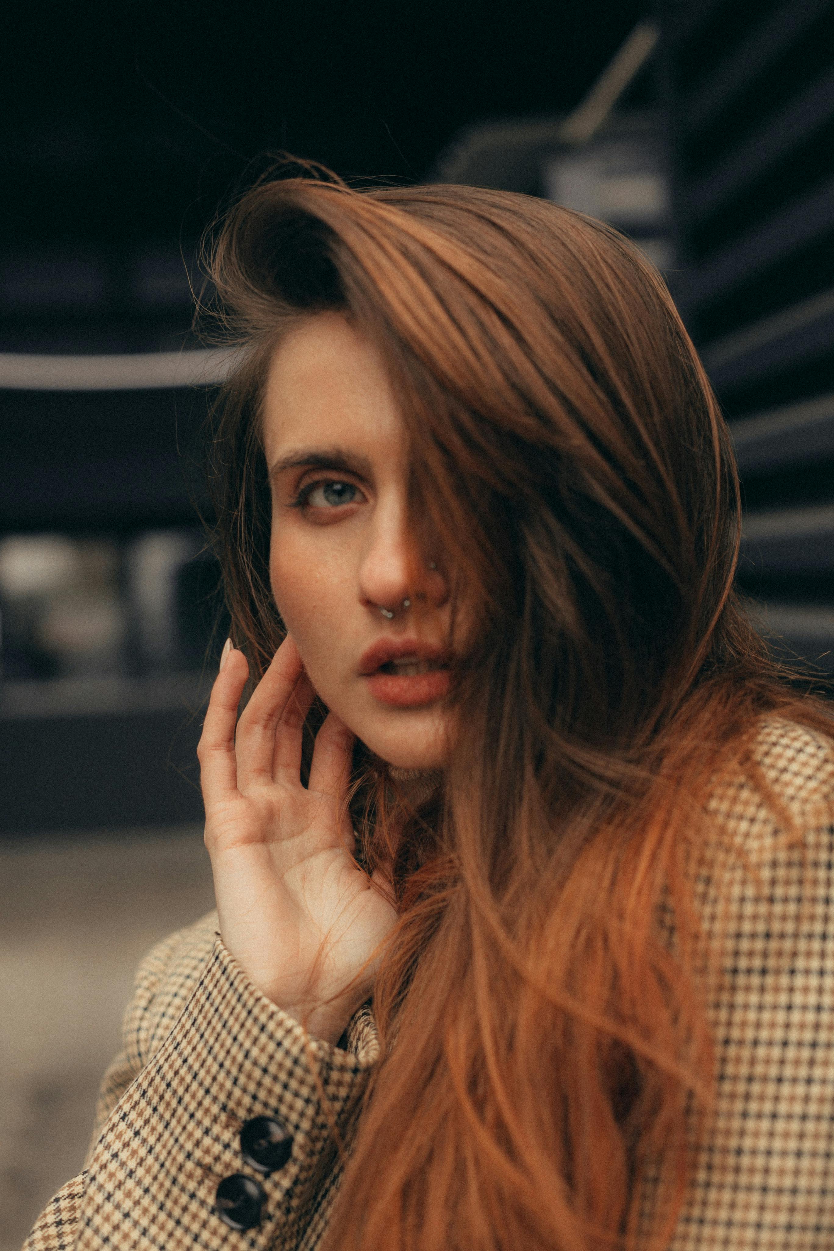 Close-up portrait of a woman with piercing, in an outdoor urban setting.