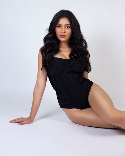 Free Attractive Hispanic female in trendy black bodysuit sitting on gray background and looking at camera Stock Photo