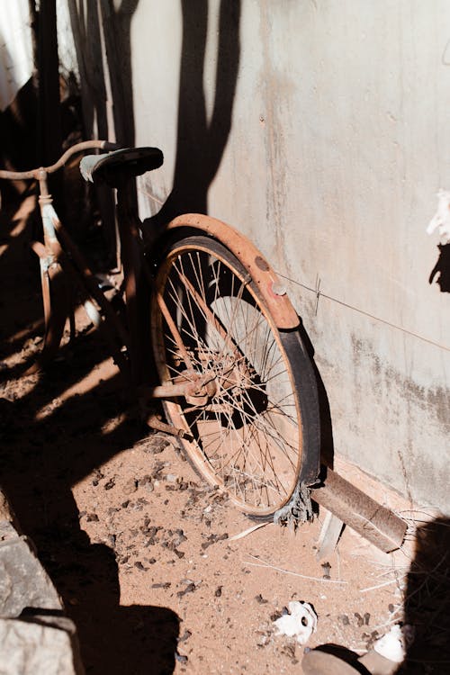 Old fashioned broken rusty bicycle near concrete building