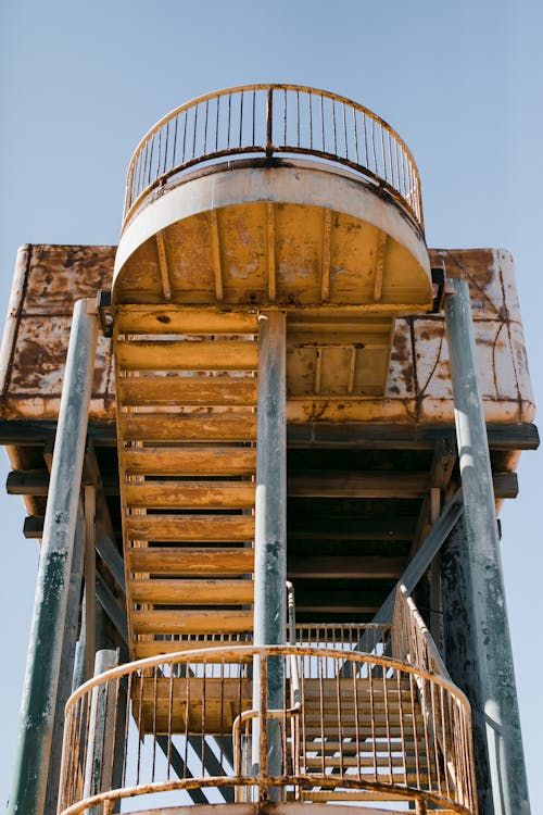 From below of metal stairway with oval railing on metal pillars of shabby building for observing territory