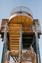 From below of metal stairway with oval railing on metal pillars of shabby building for observing territory